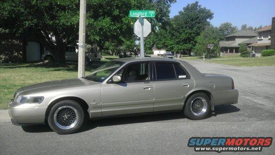 Gold 2000 Mercury Grand Marquis sedan parked on street, side view