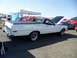 1973 Ford Ranchero - A white Ford Ranchero is parked at an outdoor event with its hood up, surrounded by other vehicles and tents.