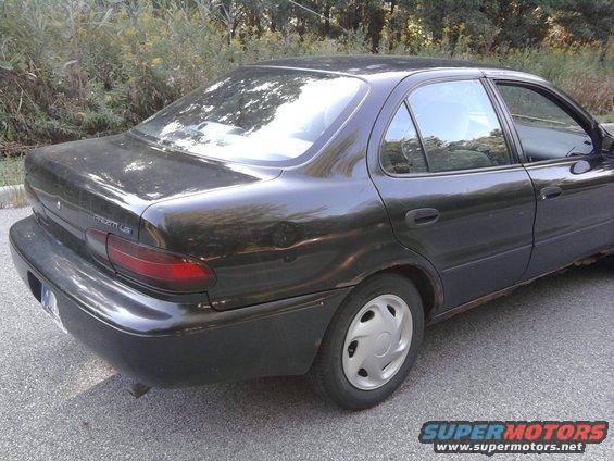 Dark sedan, rear view. Appears to be a 1995 Geo Metro