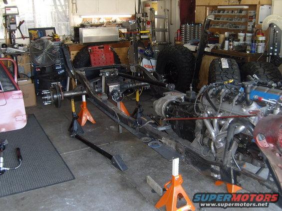 Jeep CJ frame on jack stands with engine installed in garage