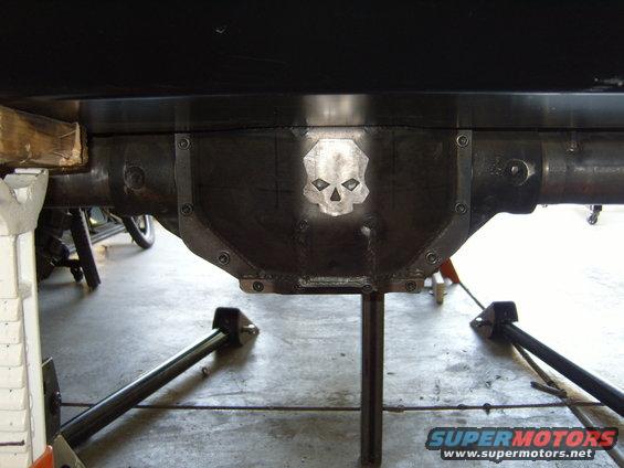 Custom differential cover with a skull emblem welded on. Vehicle is on jack stands