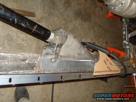 Custom suspension link mount being welded onto a frame rail. Cardboard template with notes is attached