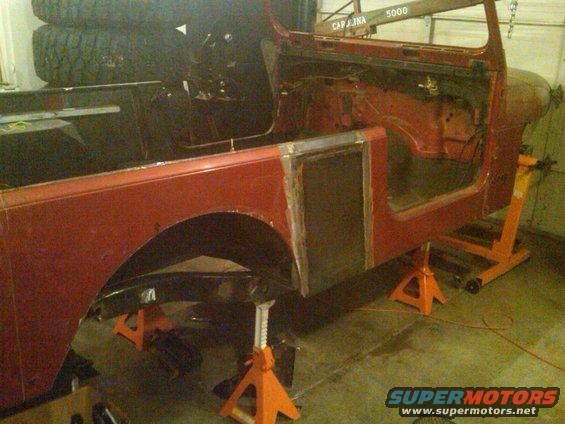 Red Jeep body on orange jack stands, undergoing repairs. Visible body panels and frame