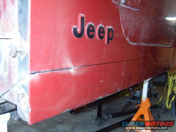 1985 Jeep CJ7 side panel with 'Jeep' emblem and a dent above the lower body line