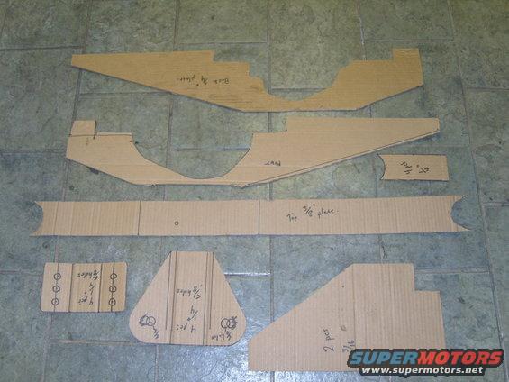 Cardboard templates laid out on a tiled floor, some with handwritten measurements and labels