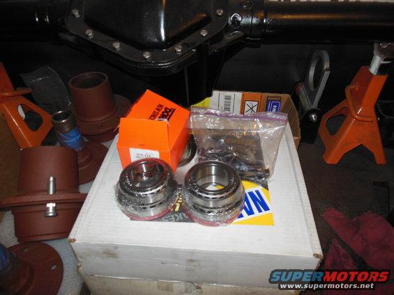 Automotive differential housing and new bearings on a box, with orange jack stands in the background