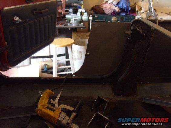 Interior of a vehicle with door panel and floor visible, tools on the floor