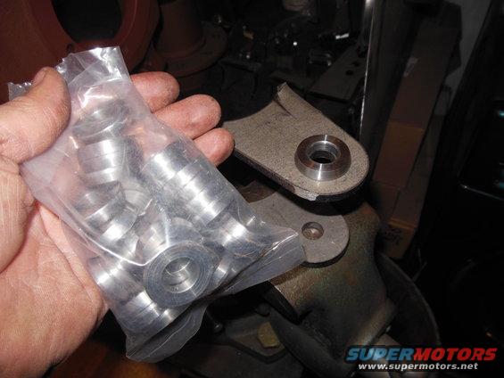 Bag of metal washers held in hand, next to a metal bracket with a circular hole