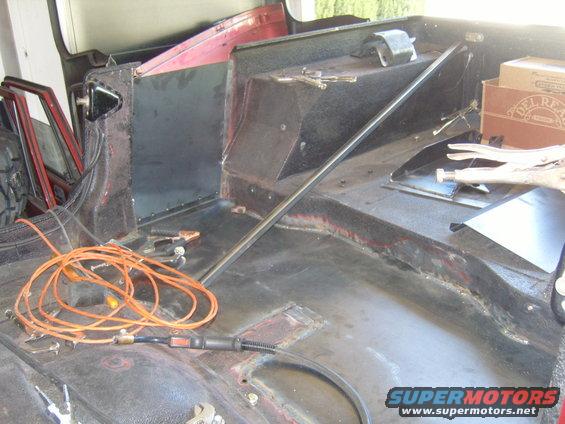 Interior of a vehicle with welding equipment and metal panels, showing repair work
