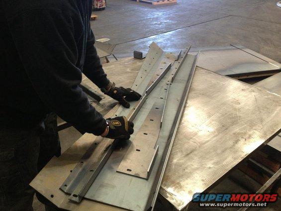 Person in gloves handling metal pieces with pre-drilled holes