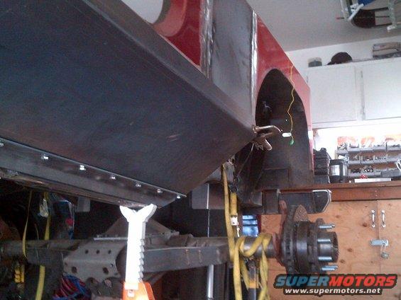 1985 Jeep CJ7 frame with body panel attached, on jack stands in a garage