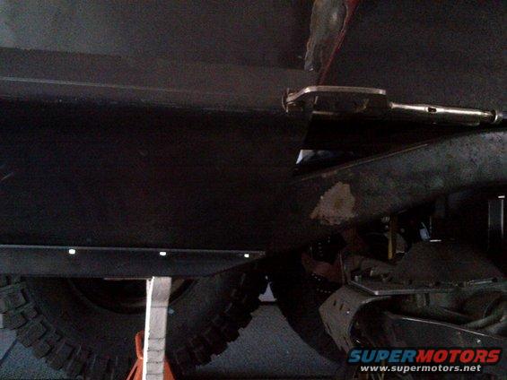 close-up of vehicle undercarriage with large tire and suspension components visible