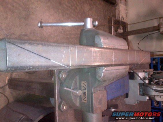 metal bar clamped in a vise with chalk marks