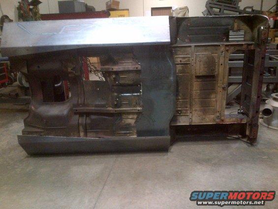 Jeep CJ body shell upside down, showing underside and some interior panels. It's in a workshop setting
