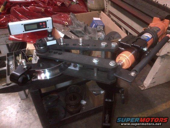 Tube bender with orange hydraulic cylinder and digital level