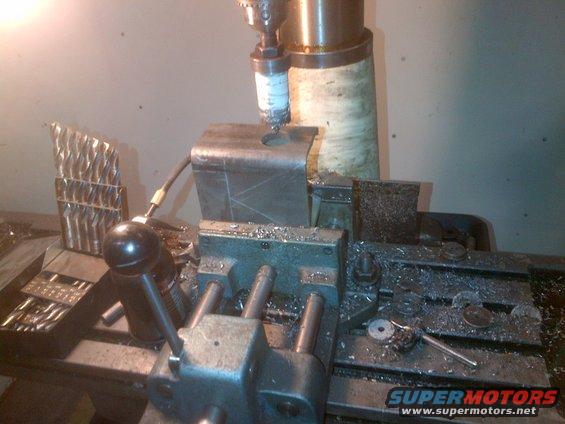 Metal part being drilled on a milling machine with metal shavings