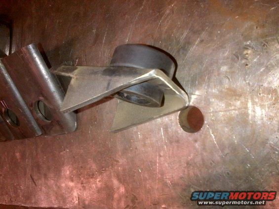 Metal bracket with a black rubber bushing, resting on a textured surface