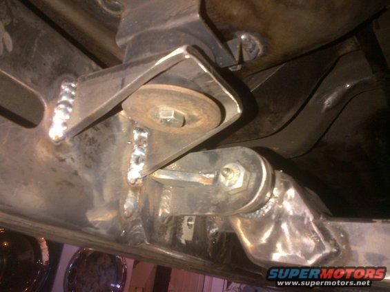 Close-up of custom welded suspension brackets on a vehicle frame, showing bolts and washers