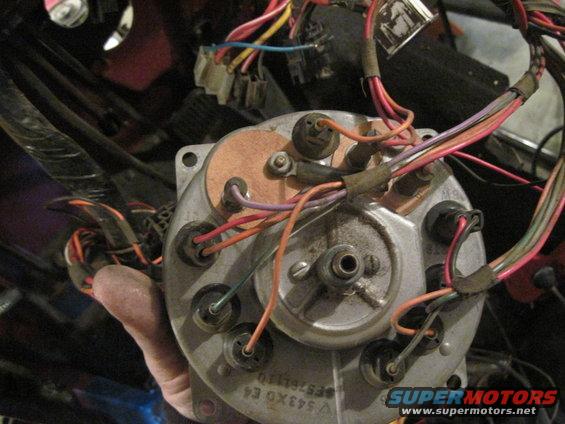 Close-up of a vehicle's gauge cluster wiring harness with many colorful wires connected to the back of the cluster