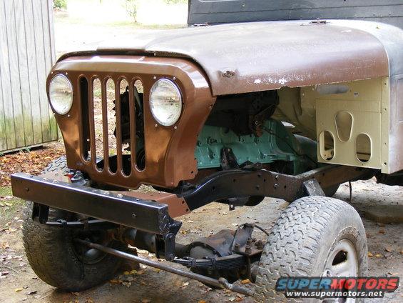 Front end of a Jeep CJ-5, showing the grille, headlights, and part of the engine. It's a project vehicle