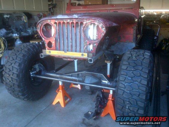Jeep CJ-series chassis on jack stands, front view, red body
