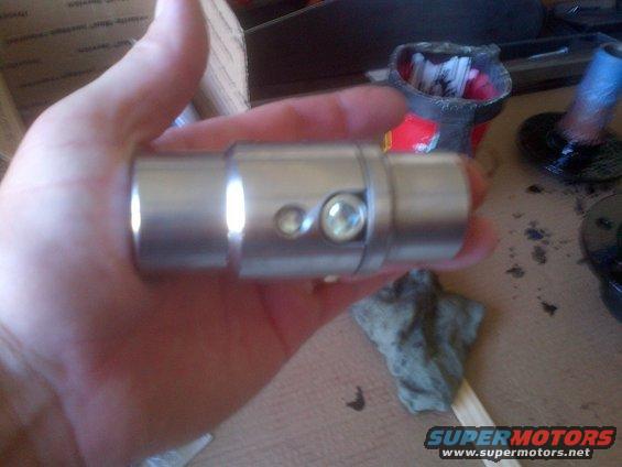 Metal automotive part with two small pins, held in hand