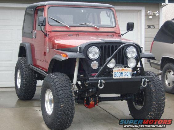 Red Jeep CJ with black hardtop, off-road tires, and custom front bumper. License plate reads BOOM SQB
