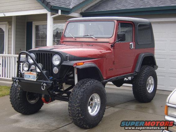 Red Jeep CJ with black hardtop and off-road tires, front bumper with lights and license plate