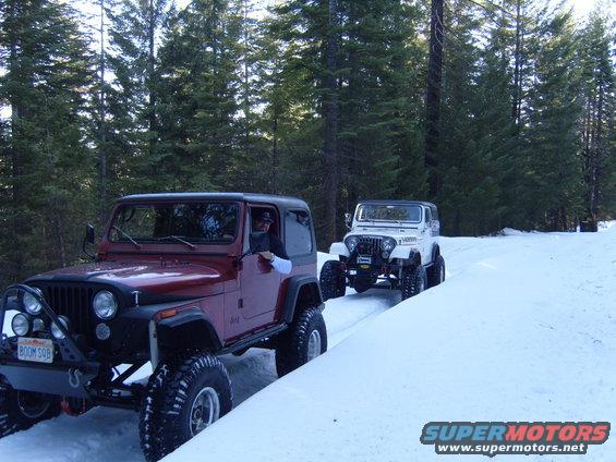 Red 1985 Jeep CJ7 leads white Jeep on snowy road