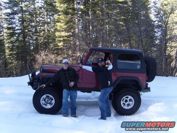 Red Jeep CJ with black hardtop and spare tire on rear, parked in snow with two men
