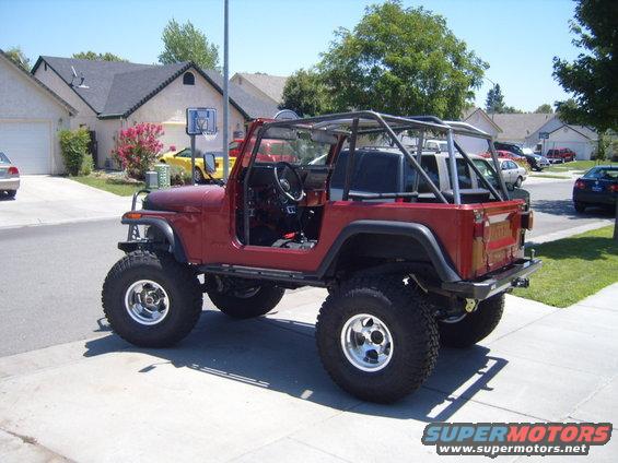 Red 1985 Jeep CJ7 with roll cage, lifted on large tires