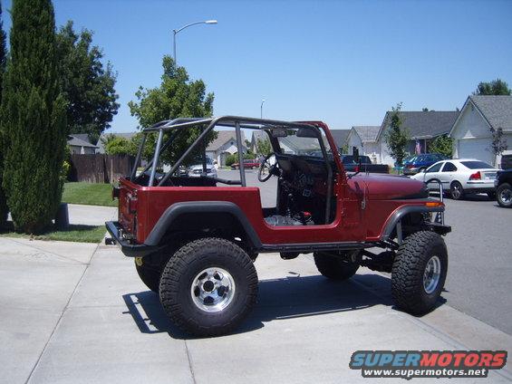 Red 1985 Jeep CJ7 with aftermarket roll cage, doors removed, parked on a suburban street