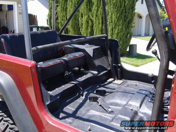 Red Jeep CJ interior with black seats and roll cage. Floor is black textured