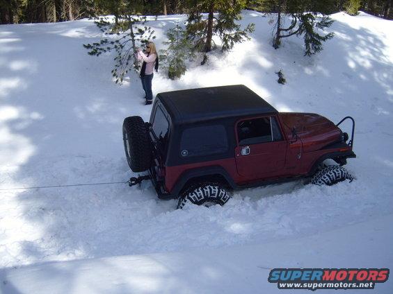 Red Jeep stuck in deep snow, with a person standing nearby