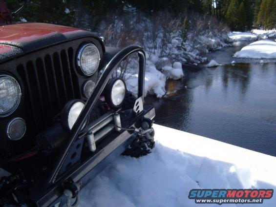 Jeep CJ front end with winch, parked in snow next to a partially frozen river