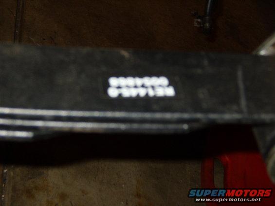 Black metal part with white text reading RE1445.0 0054868