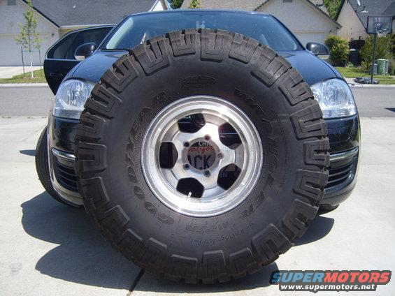 Spare tire obscuring the front of a black car. The tire has 'GOODYEAR' visible
