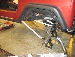 1985 Jeep CJ7 rear fender well with suspension parts visible, vehicle on jack stands