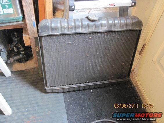 Automotive radiator with a metal cap on top, sitting on a dark mat