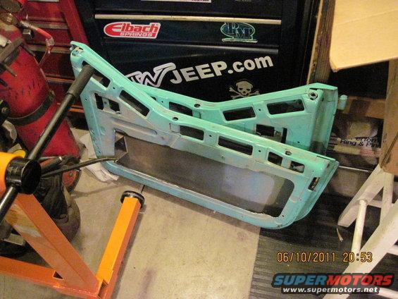 Two teal Jeep doors disassembled and resting on a stand