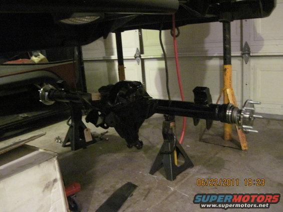 rear axle assembly on jack stands in garage, part of a vehicle is visible above