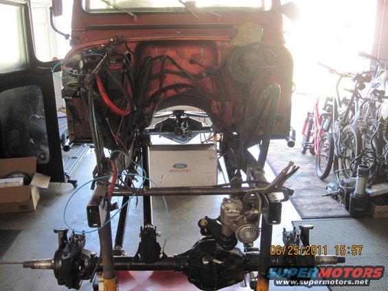 orange vehicle body on stand, front axle and drivetrain exposed, Ford fuel tank visible