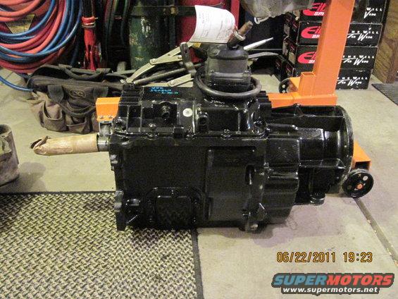 Black Jeep transmission with a tan-wrapped output shaft, mounted on an orange engine stand