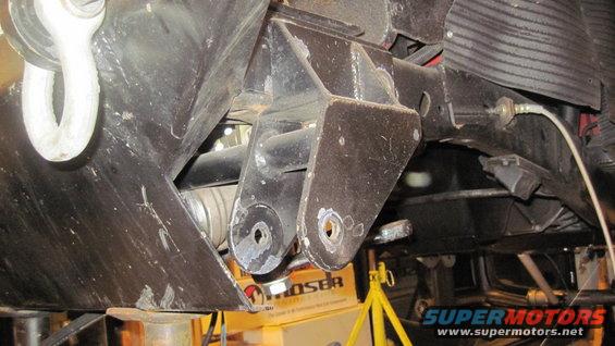 close-up of vehicle's undercarriage showing suspension brackets and a tow hook