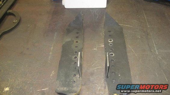Two black metal parts with rows of holes and metal tabs
