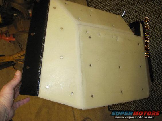 Black metal bracket attached to a cream-colored, angular part with visible screw holes