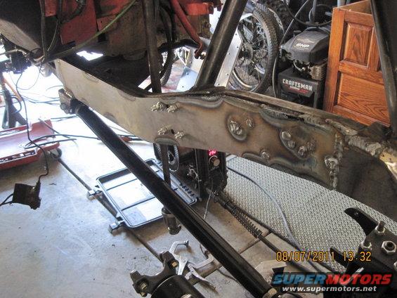 Welded frame section with suspension components and a Craftsman engine in the background