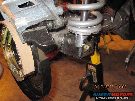 Rear axle assembly with brake caliper and coil spring on jack stand