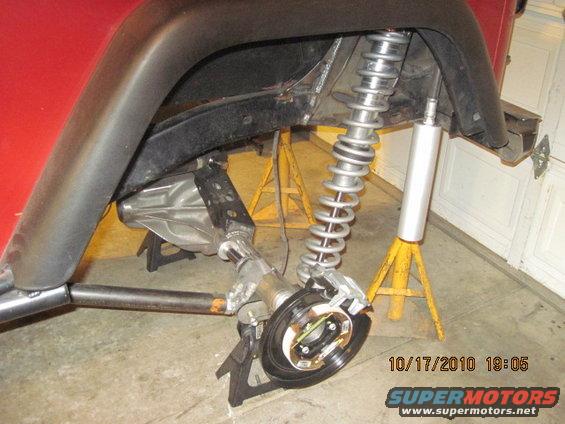 Jeep CJ rear axle assembly on jack stands, showing shock absorber and brake components