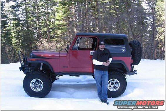 Man standing next to red 1985 Jeep CJ7 with black hardtop in snow